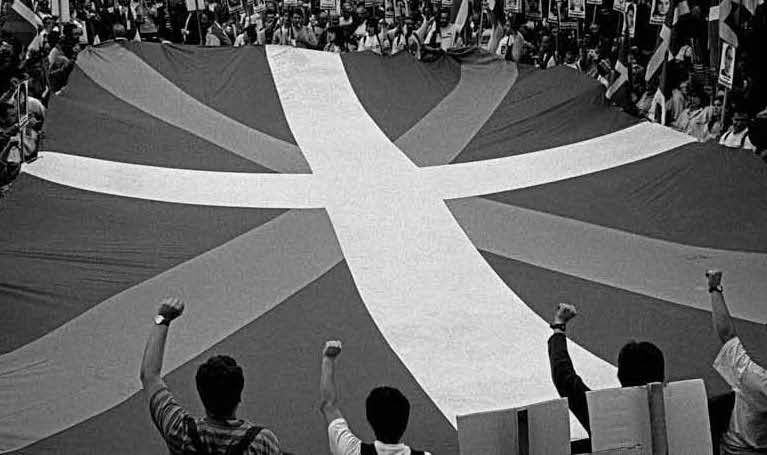 Black and white picture of mass protest surrounding a flag.